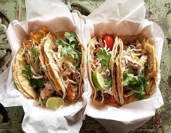 four tacos with meat, arugula, lime, tomato